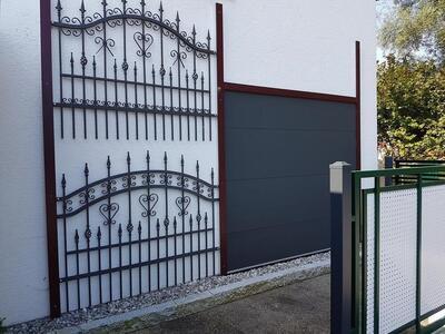 Ausstellung von einem Eisen-Gitter-Tor und einem Garagentor an einer weißen Wand präsentiert