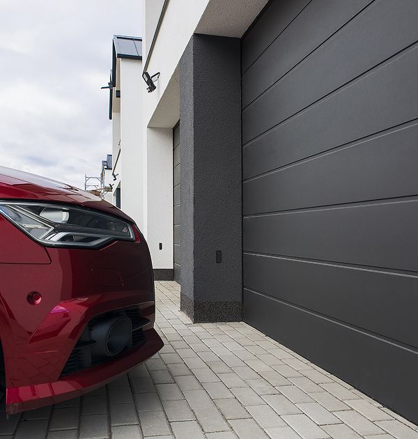 Ein rotes Auto steht vor einem Garagentor geparkt.